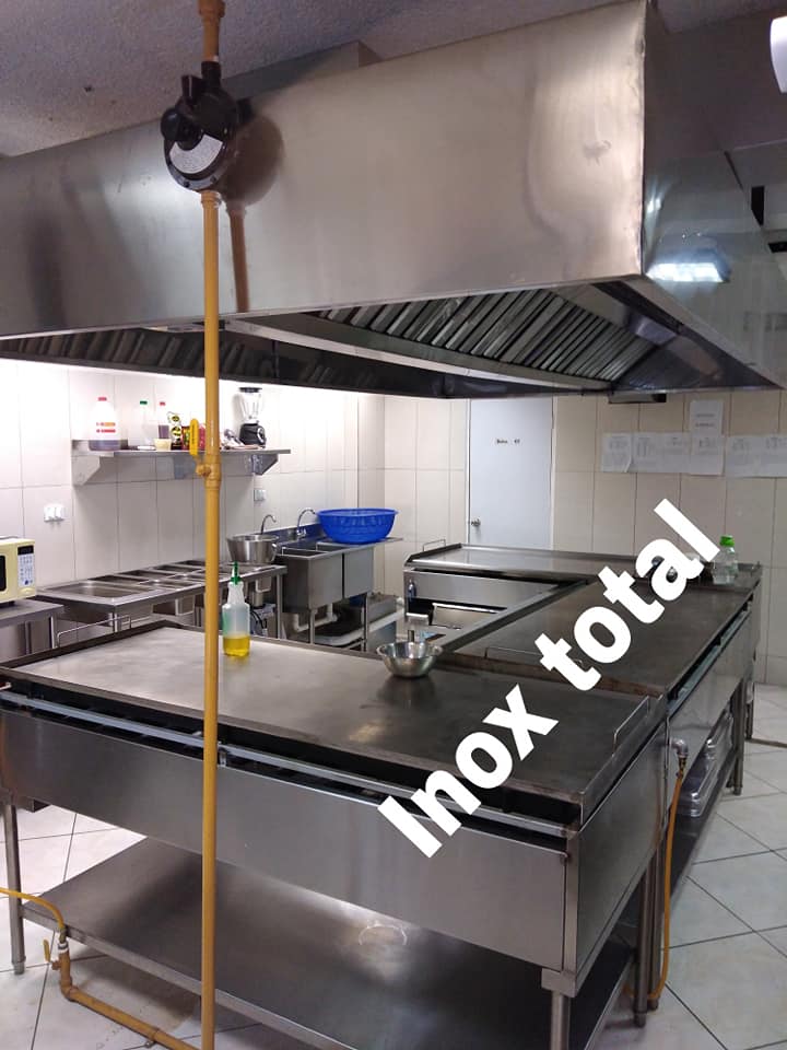 Plancha industrial y campana extractora de acero inoxidable en cocina profesional