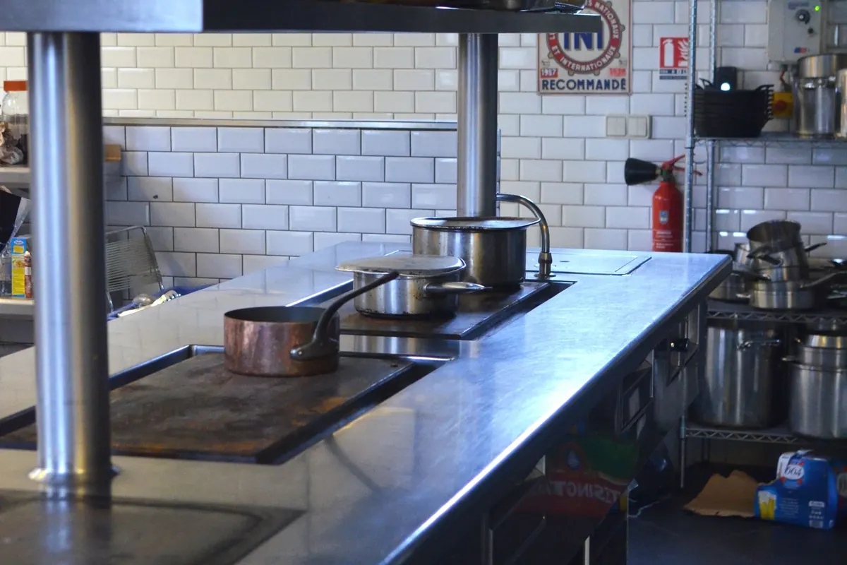 Inicio Cocina industrial en acero inoxidable con mesa de cocción y ollas